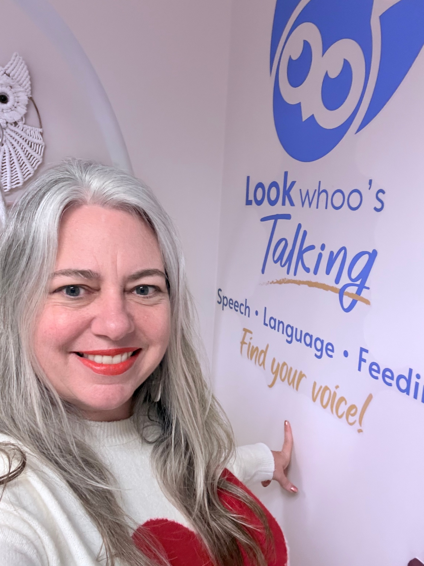 Chelsea smiling next to the Look Whoo's Talking logo wall